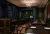 Image shows a restaurant and bar render for Ink & Oak, showing dark green and blue panelled walls, warm timber furniture, banquette seating, chandelier, ornate ceiling mouldings, red curtains and warm layered lighting. 