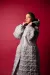 Model in front of a red backdrop wearing a wadded silver coat which hast quilting details