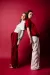 Two models in red and white outfits leaning against each other in a red setting