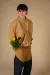 Model stands in studio wearing camel crewneck with denim a suede jeans with red and yellow roses placed inside jeans pockets