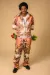 Male model wear floral jumpsuit with symmetric print and has red and yellow roses in pockets