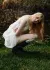 Model crouching in a bubble dress and wellies with a pond in the background.