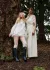 Two models standing close together against a tree. One in a sheer bubbly dress and the other in a sheer top and gathered wide-leg trousers.