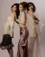 Three models wearing flowing satin and silk outfits against a white backdrop