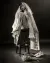 Third model sitting on a chair wearing a long white silk bridal dress against a black backdrop
