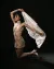 Third model kneeling on the floor wearing a beige lace-detailed minidress and holding a white veil 