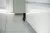  A black rabbit peeks out from behind a kitchen cabinet in a low-angle close-up.