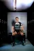 A rugby player in a black and white kit sits holding a rugby ball in a dark locker room.