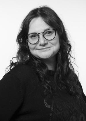 a woman wearing glasses and smiling at the camera