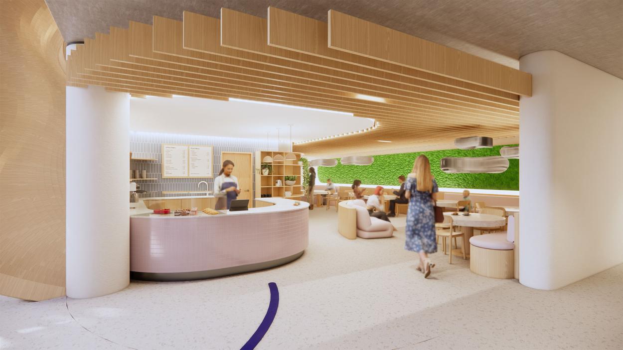    Pictured is a café with a counter and seating, filled with people. There are beams on the ceiling and a moss installation, as well as bespoke lighting. 