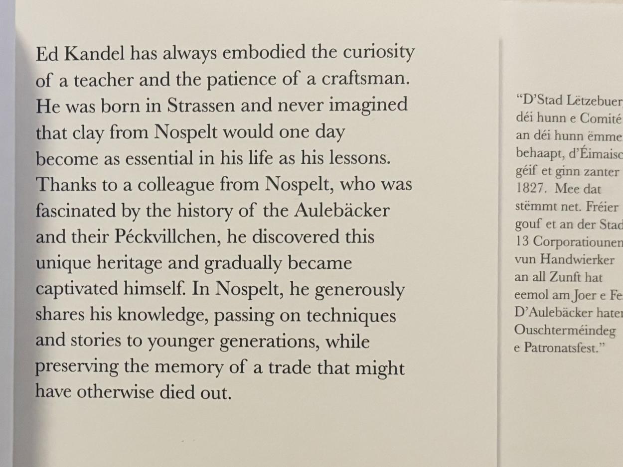 A clean typographic layout featuring a text profile of craftsman Ed Kandel on a narrow-cut page that reveals a sliver of Luxembourgish narrative from the spread beneath.