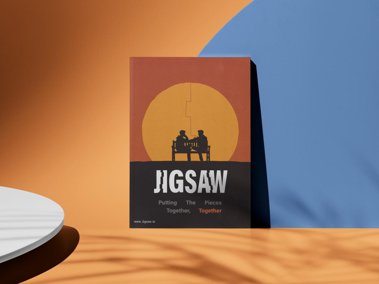2-	A poster displayed in a bright and colourful room, the poster displays two people sitting on a bench speaking infront of a vibrant sunset, the logo is in the centre with the tagline “Putting The Pieces Together, Together” written under.