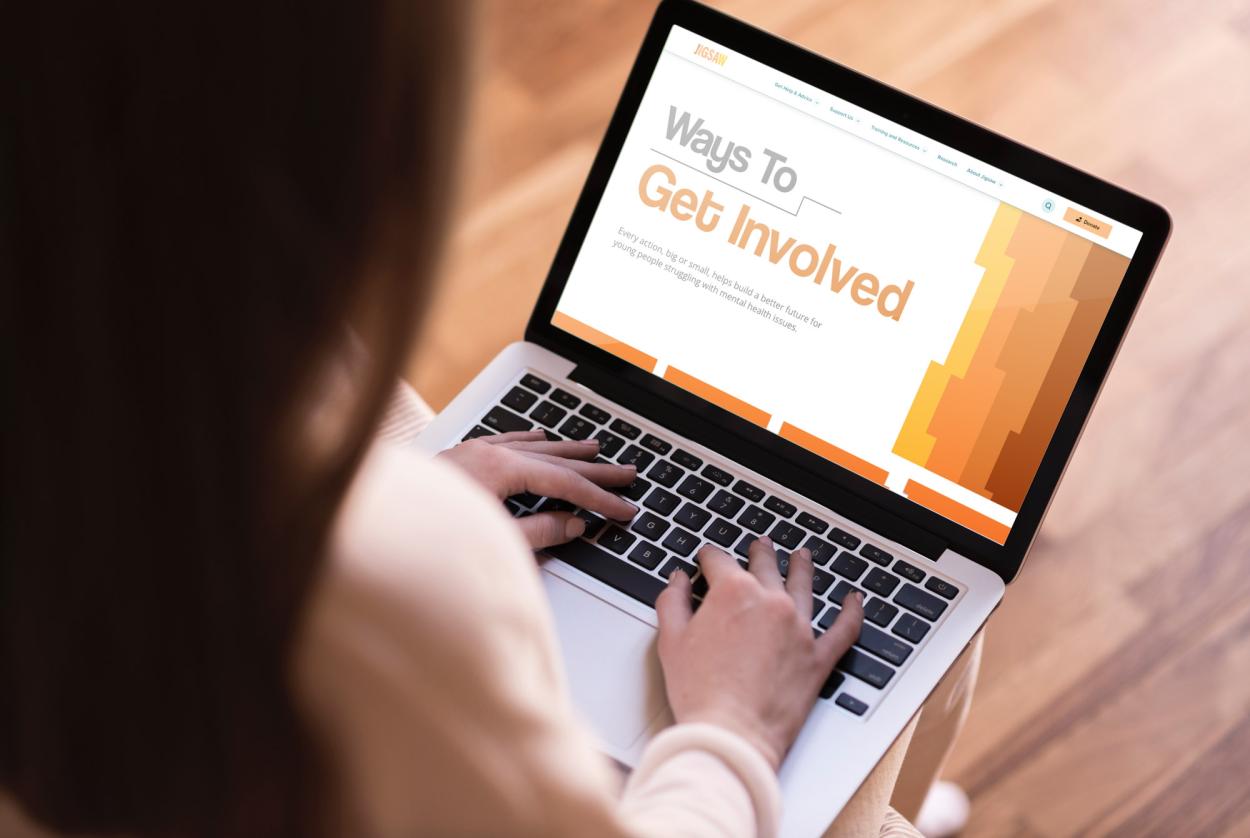 3-	A laptop screen is show displaying the Jigsaw.ie website on the “Get Involved” tab, the page features the brand’s pattern of interlocking puzzle shapes