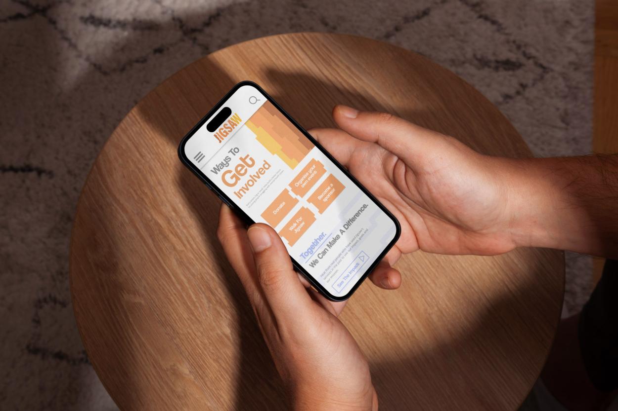 5-	A phone screen is show displaying the Jigsaw.ie website on the “Get Involved” tab, the page features the brand’s pattern of interlocking puzzle shapes