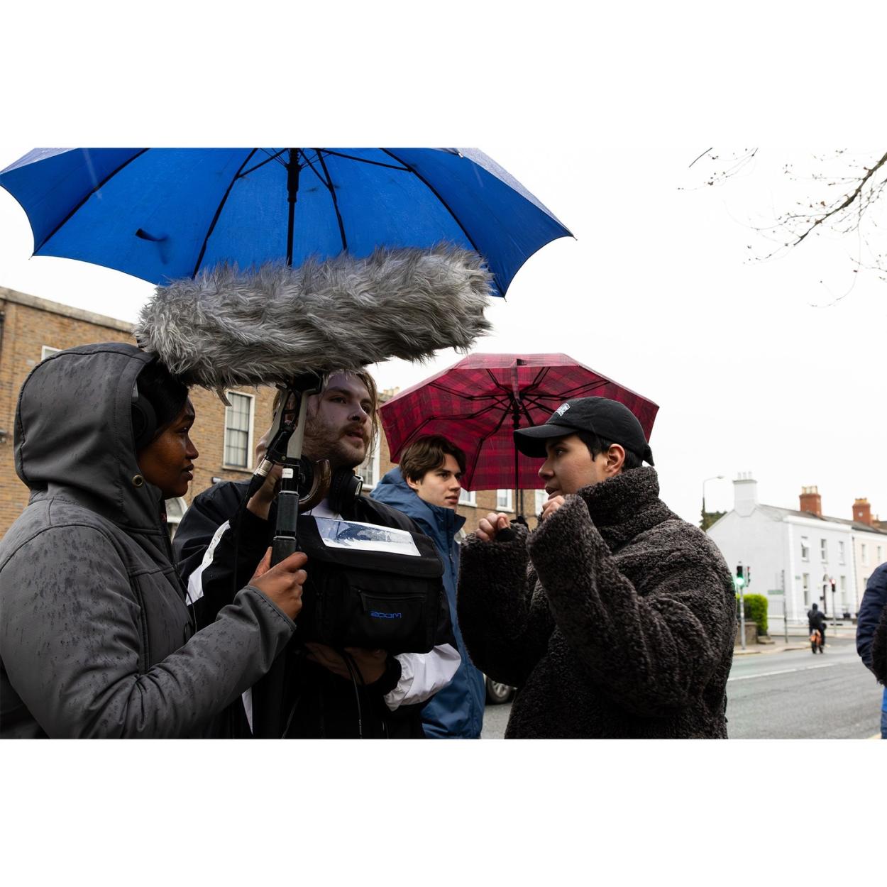 a group of people standing in the rain holding an umbrella