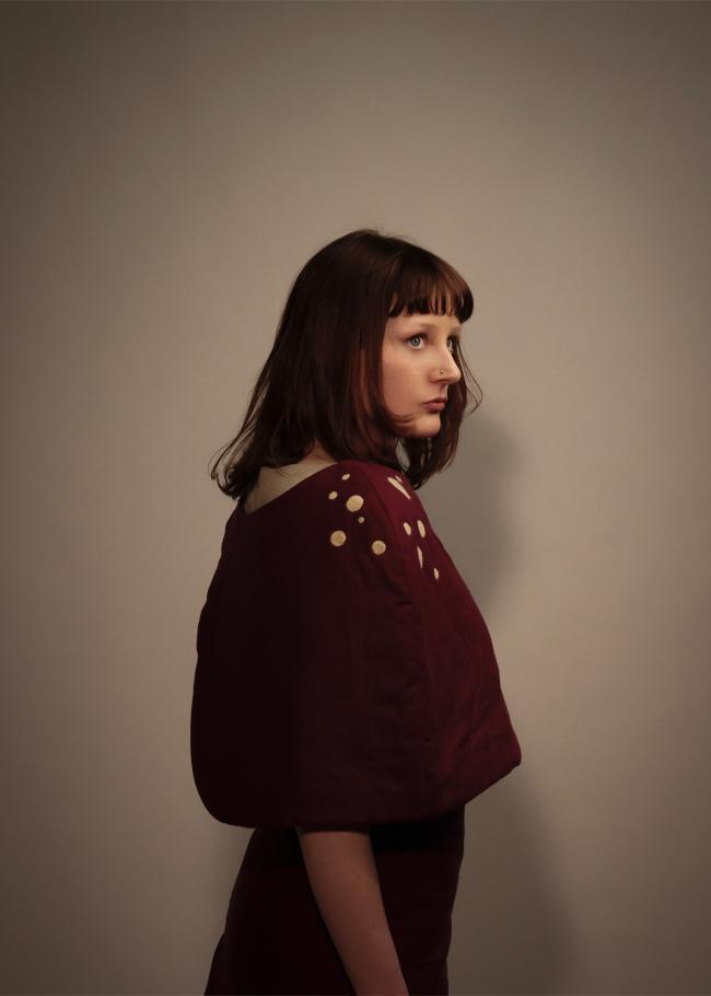 Model wearing shawl with needle felted embellishment on shoulder