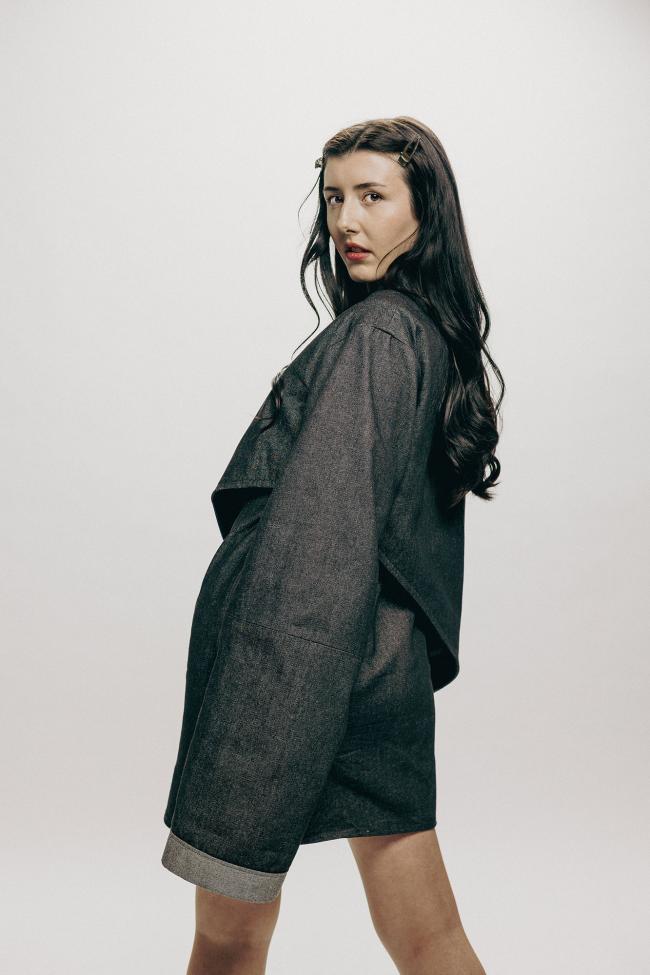 A model posing to show off sleeve details and cloak.