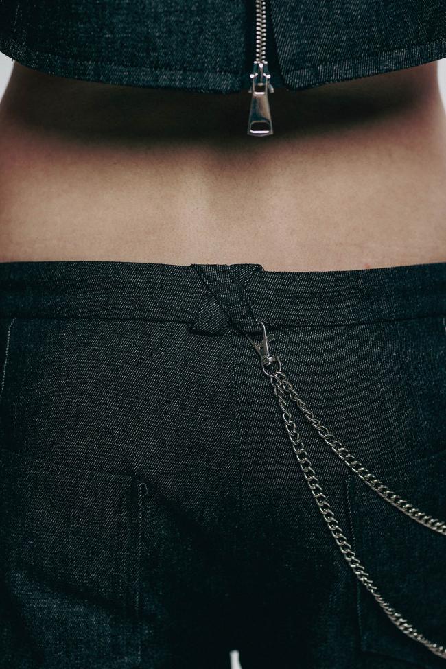 A close-up belt loops, waistband, chain detail and zipper.