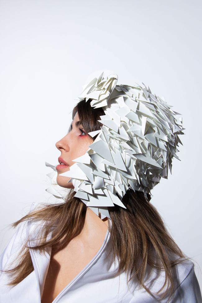 A side profile, close-up of a model wearing a white sequined hat 