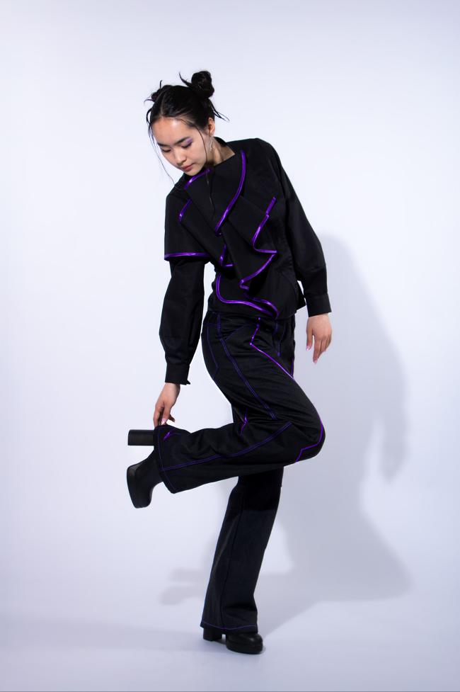 Model wearing draped blouse and jeans with piping
