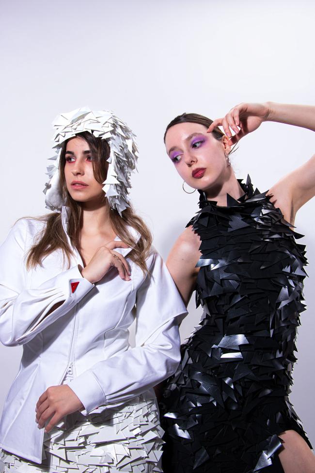 A model wearing a white sequined hat and white shirt, a second model wearing a long black sequined dress.