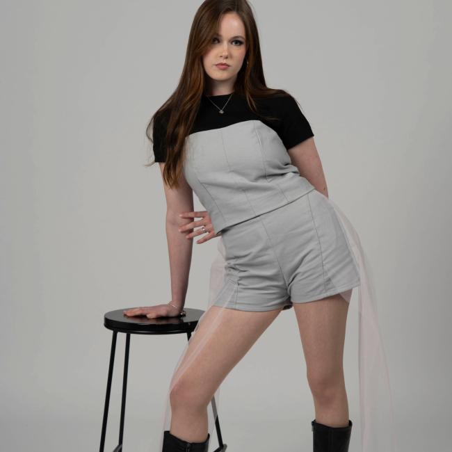 Model wearing a black and grey top with grey shorts