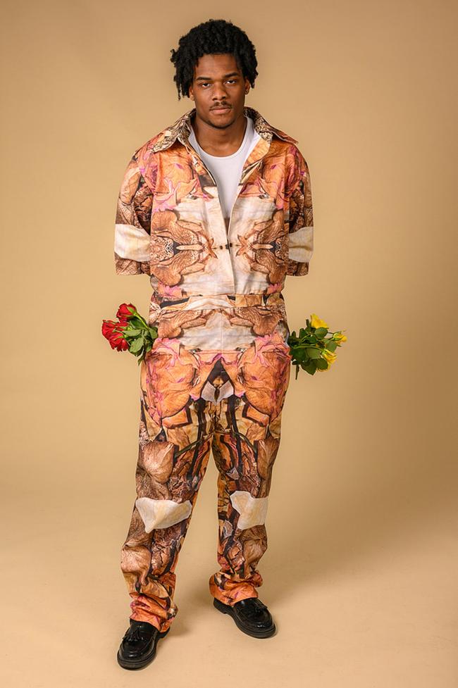 Male model wear floral jumpsuit with symmetric print and has red and yellow roses in pockets