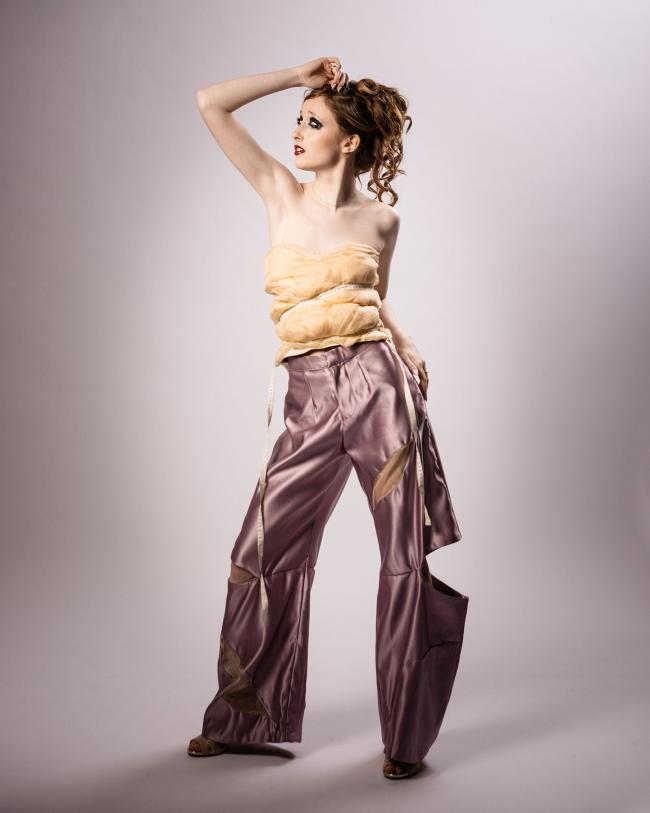 Second model wearing lilac satin trousers and a beige draped silk top against a white backdrop