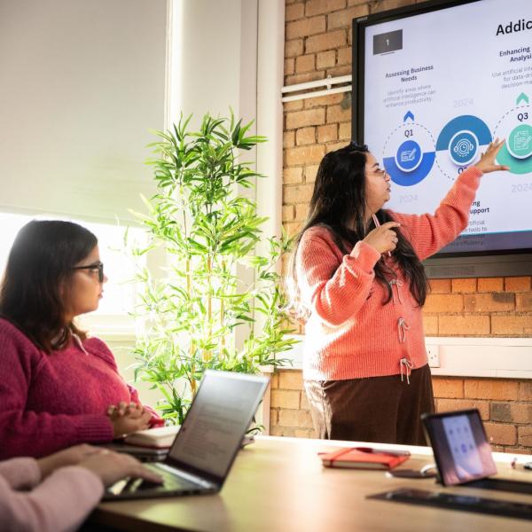 a group of people sitting at a table using a laptop