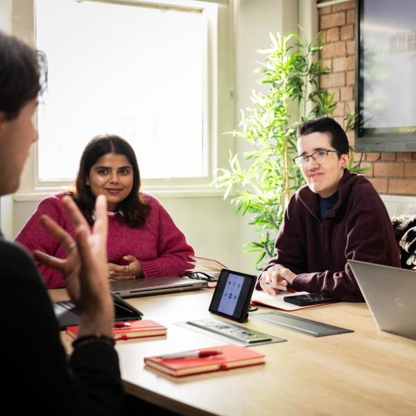 a group of people sitting at a table using a laptop computer