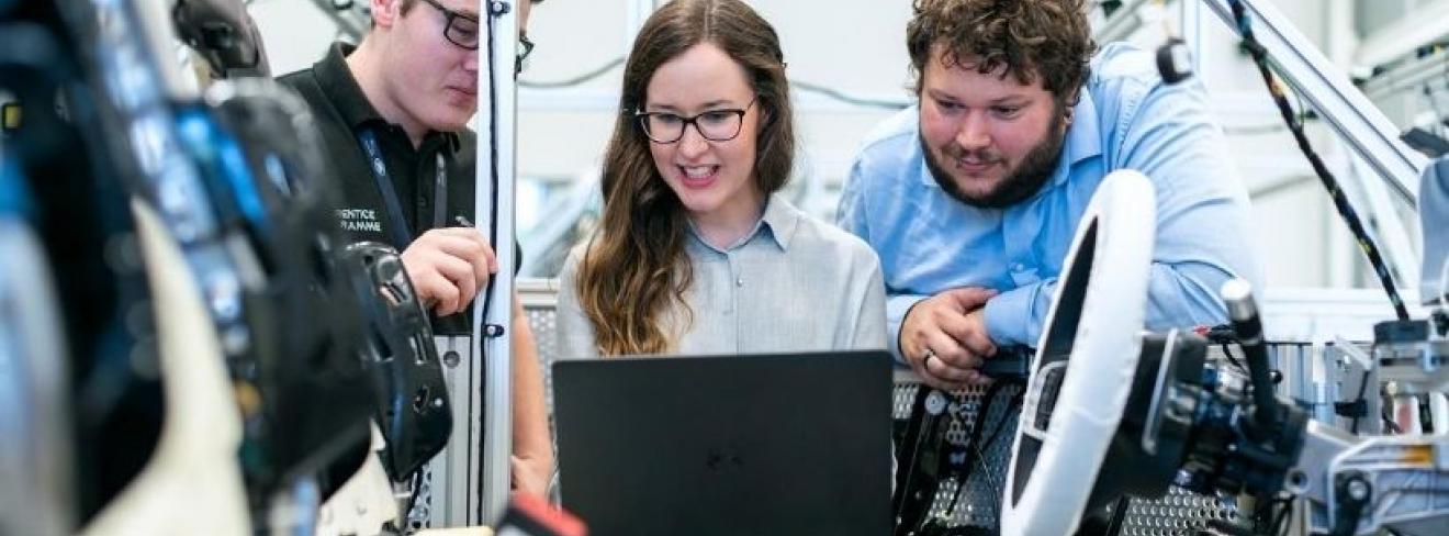 Three apprentices around a computer